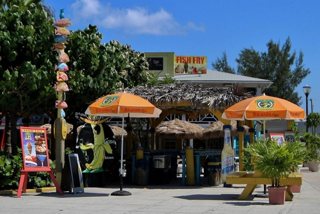 Colorful shacks at Arawak Cay, bustling with activity as locals and tourists enjoy authentic Bahamian dishes and vibrant island vibes.