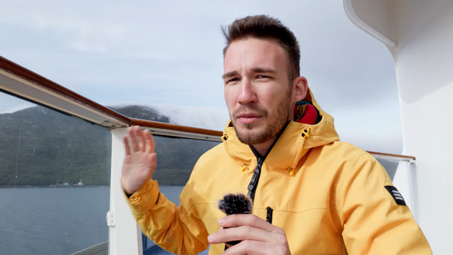 Krisztian in a yellow windbreaker onboard a cruise ship cruising through South American fjords.