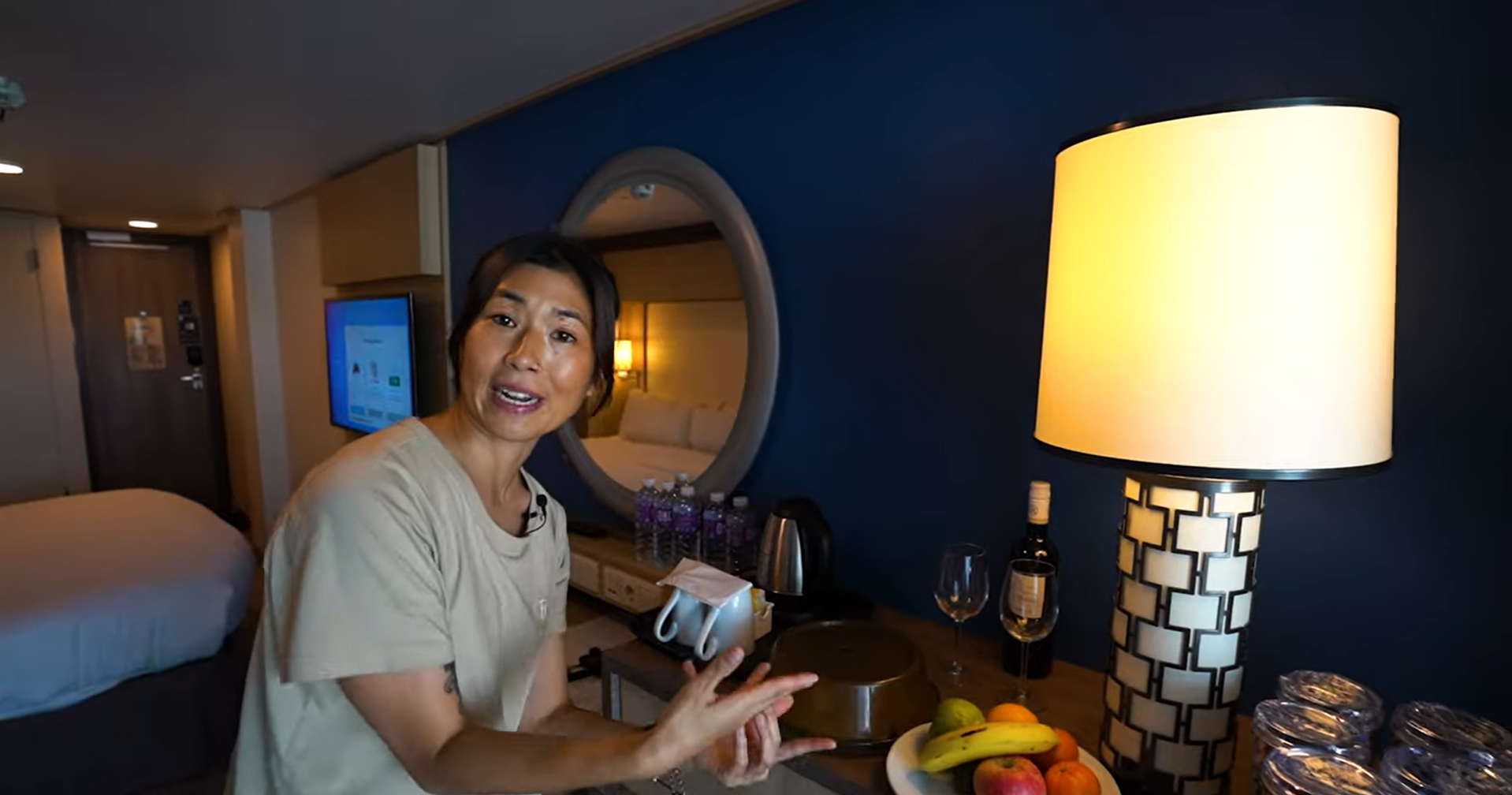 Asian lady exploring and showing off a Royal Caribbean cruise cabin.