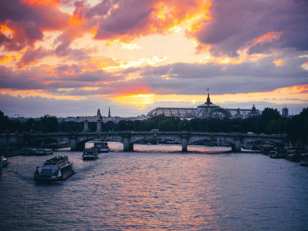 Beautiful sunset view of the Seine River and bridges in Paris with vibrant skies.