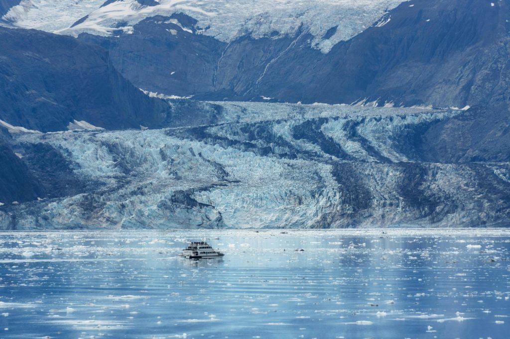 A breathtaking aerial view of a glacier in Alaska with a ship navigating icy waters.