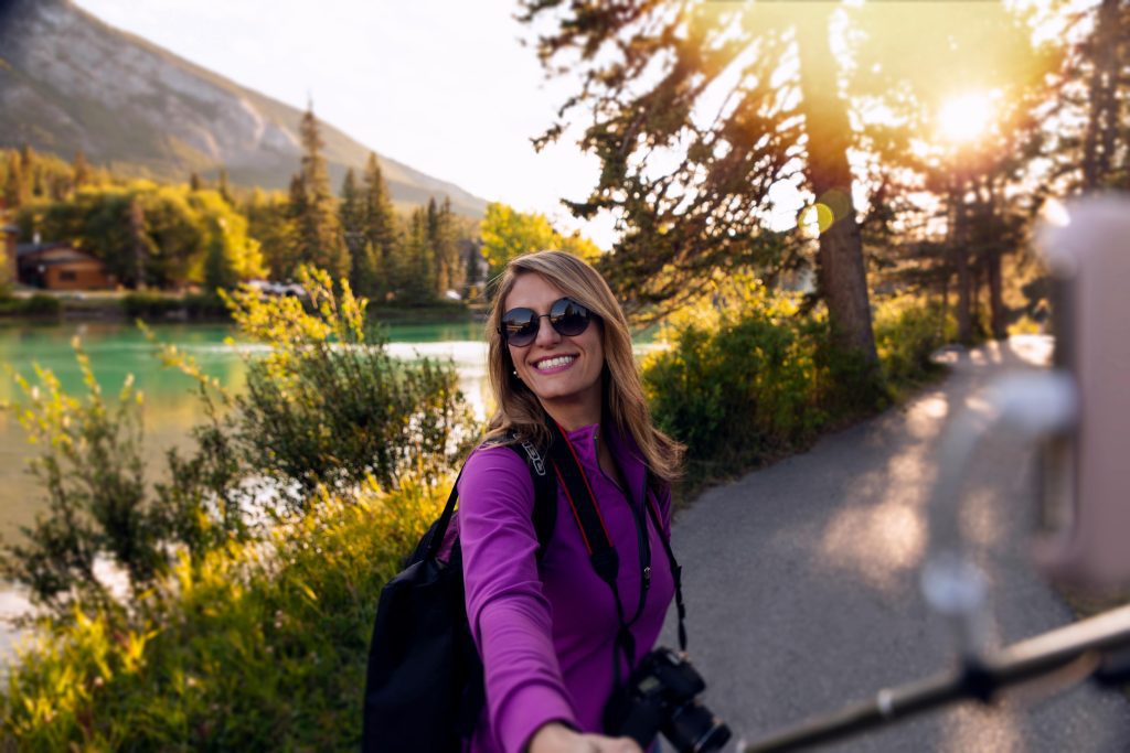 A joyful woman takes a selfie in the stunning outdoor landscape of Banff, Canada.