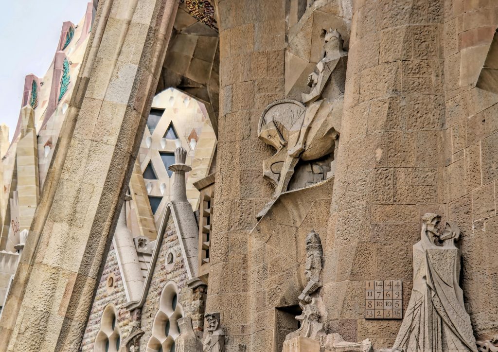 Detailed view of the sculptures and architectural design on the Passion façade of La Sagrada Família, Barcelona, featuring a magic square.